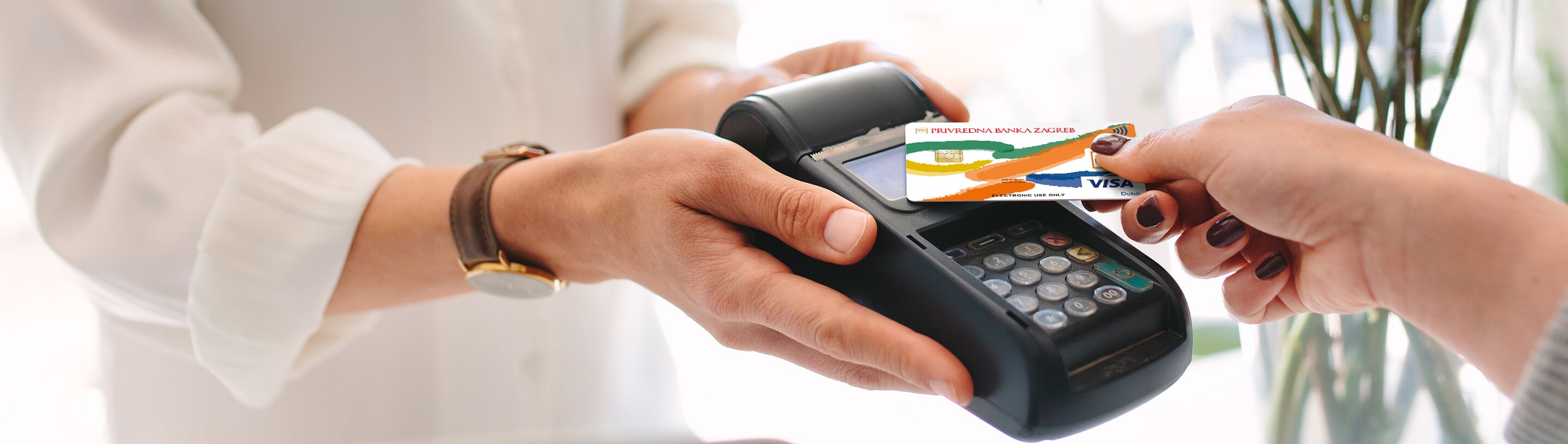 Visa Inspire kartica u ruci prislonjena na POS uređaj.