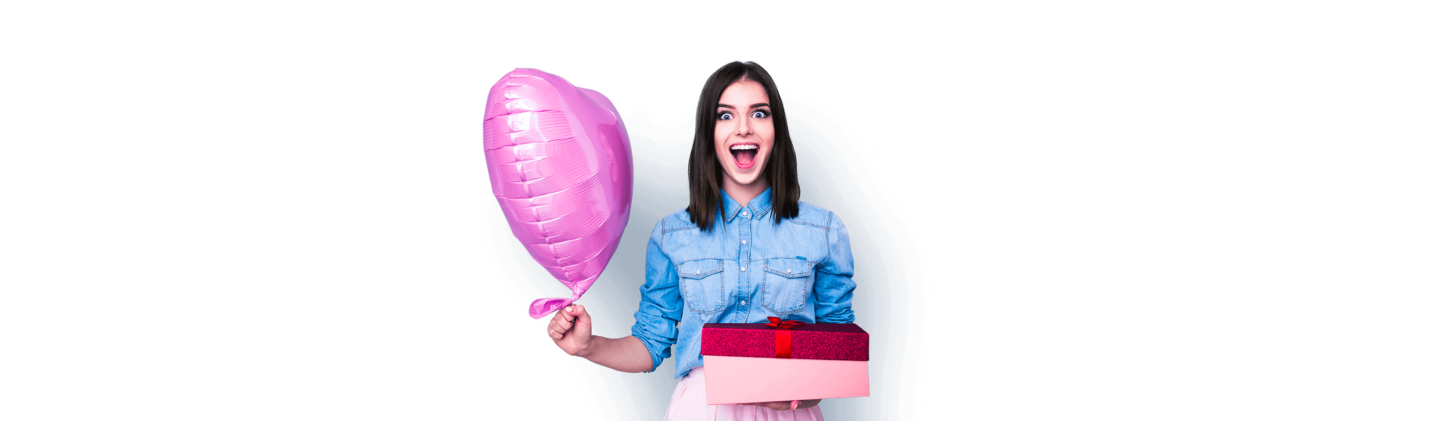 Vesela mlada djevojka u jednoj ruci drži rozi balon u obliku srca, a u druoj ruci poklon kutiju.