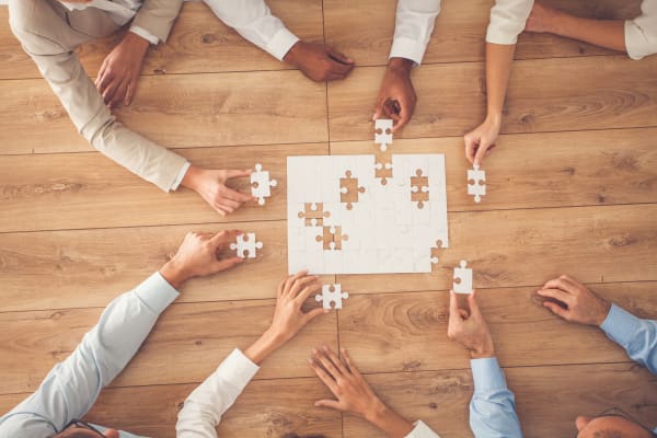 Plusieurs mains de gens de différentes nationalités qui font un puzzle ensemble